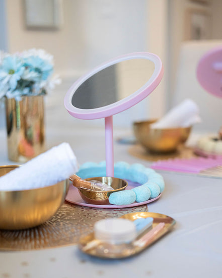 Pink vanity mirror on a table with decorative items