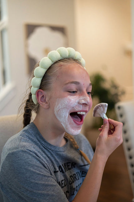 Person applying a facial mask with a brush in a home setting