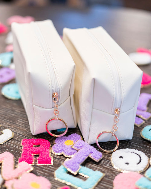 White quilted pouch with keychains on a wooden surface