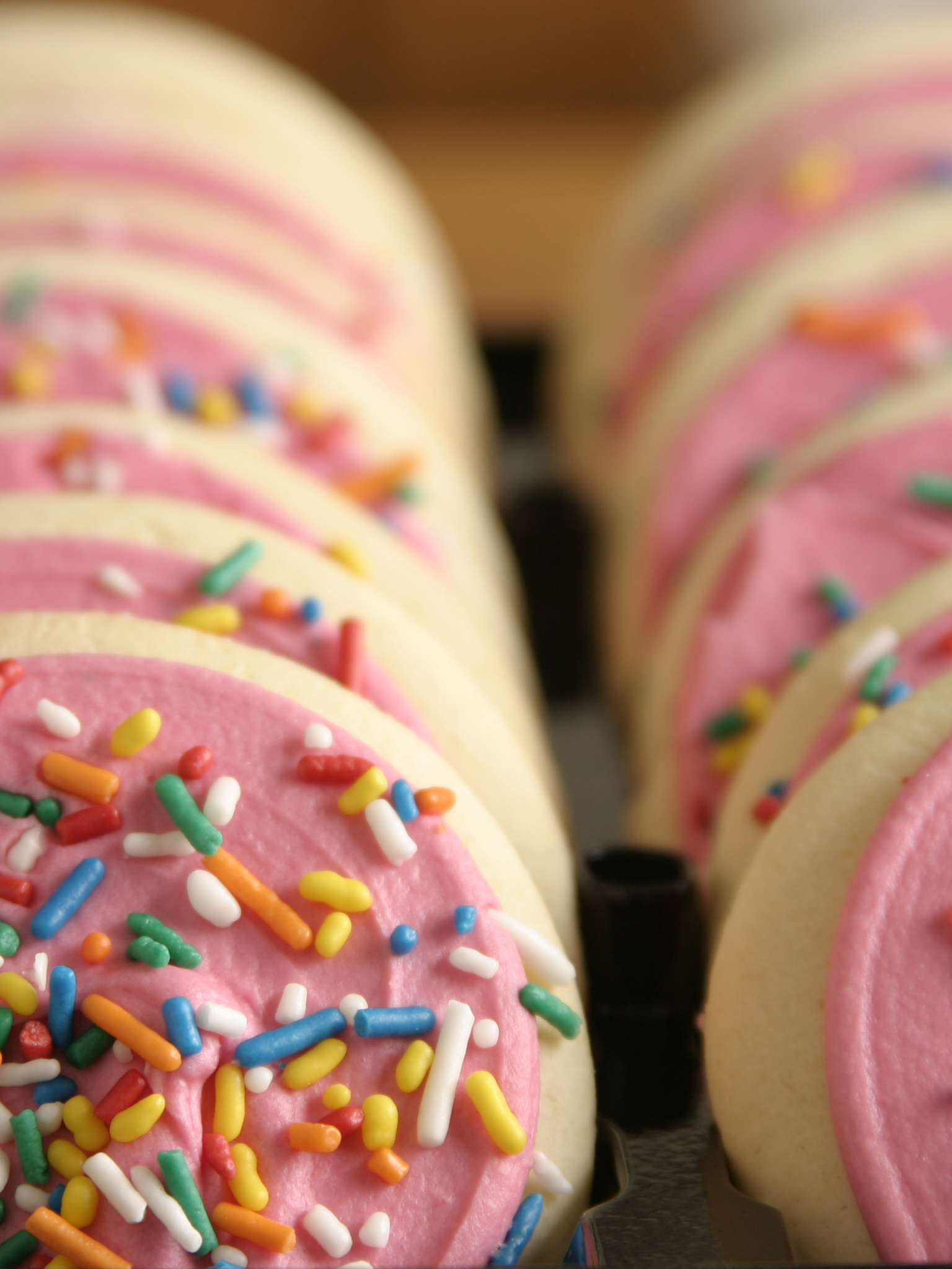 Pink frosted cookies with colorful sprinkles 