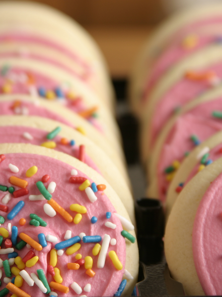 Pink frosted cookies with colorful sprinkles 